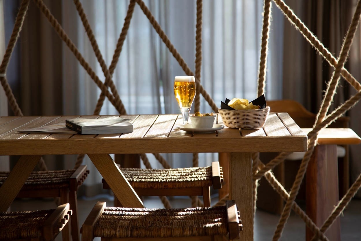 Table en bois avec bière, chips et livre à Casual Bahía Ibiza, hôtel près de la plage.