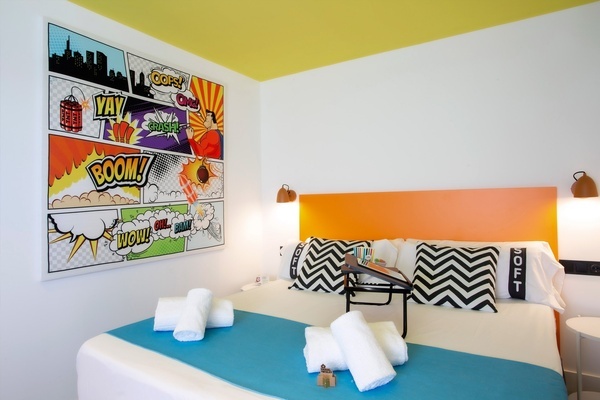 una habitación con una cama y una pintura en la pared que dice boom
