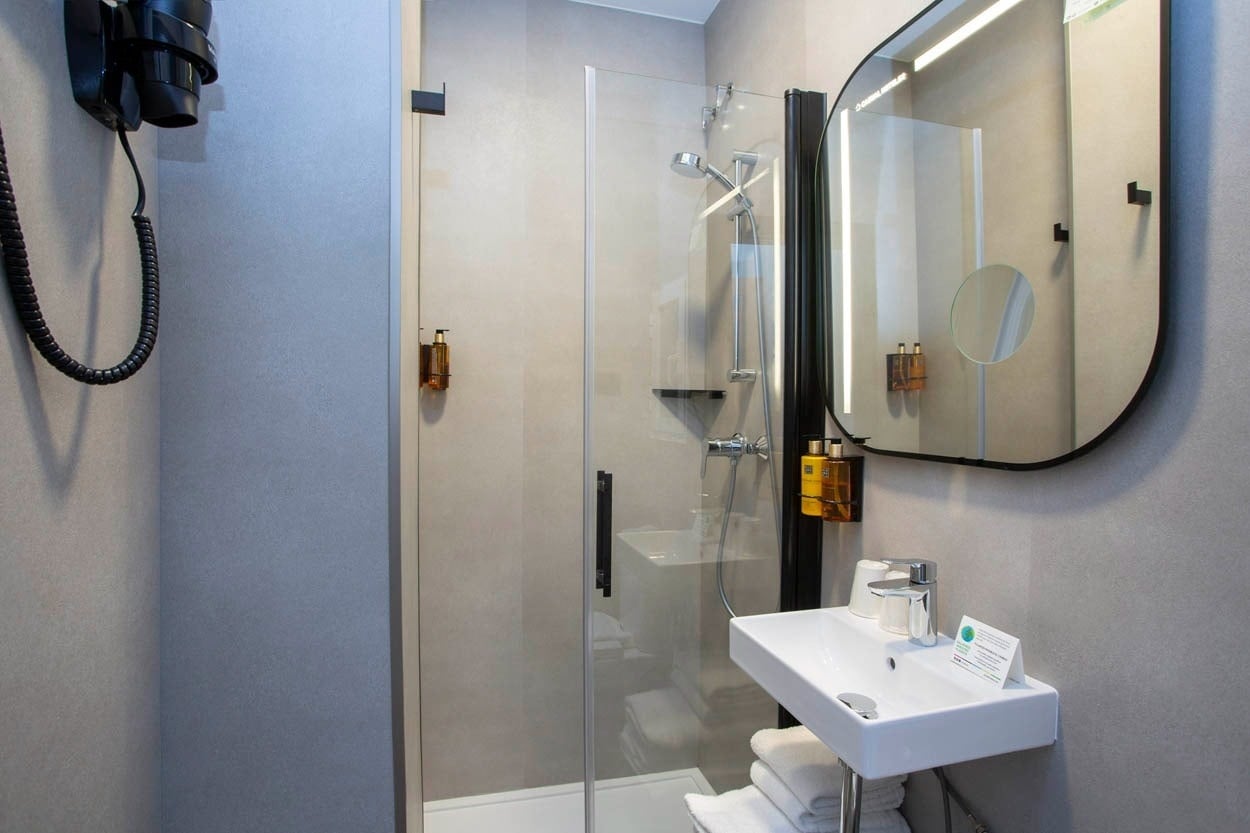 Modernes Badezimmer mit Dusche, Waschbecken und Spiegel im Casual del Cine Valencia - Themenhotel in Valencia.