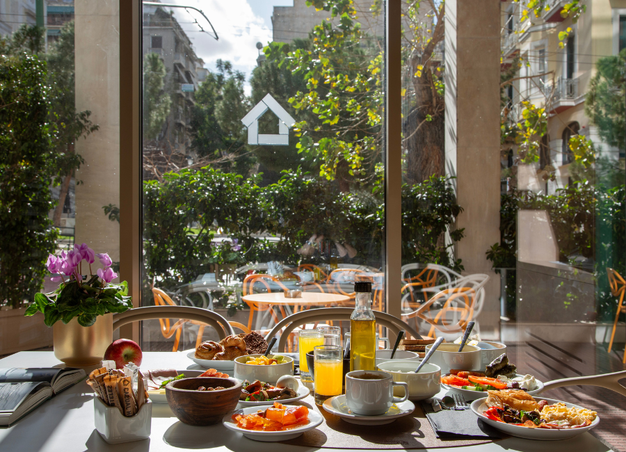 Delicious hotel breakfast spread by a window with a sunny outdoor view and garden.