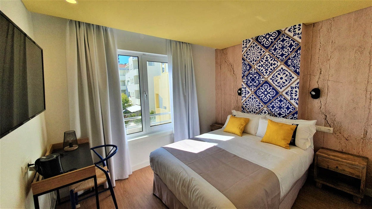 Camera accogliente con letto matrimoniale e decorazione a mosaico, ideale per il tuo soggiorno al Casual Raízes Porto - Boutique hotel.