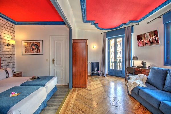 een hotelkamer met twee bedden en een blauwe bank