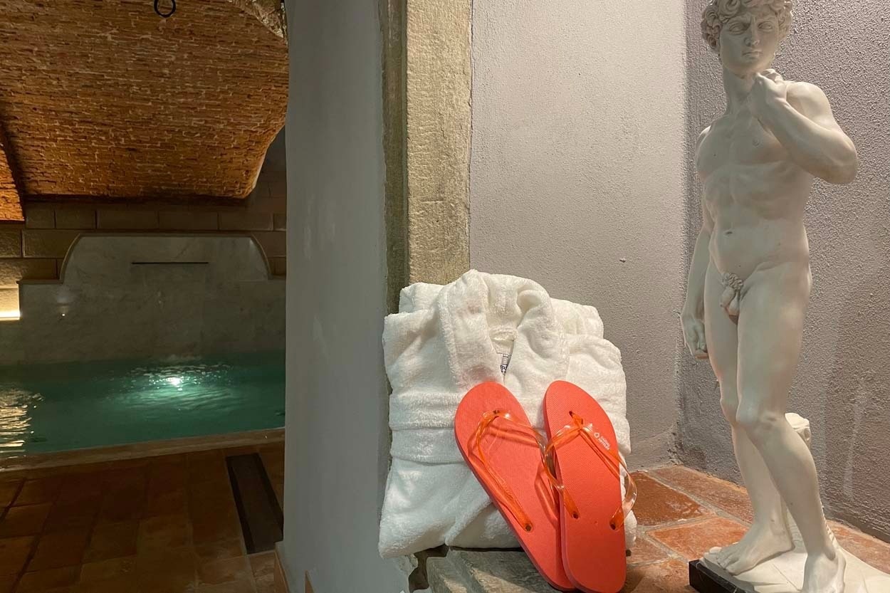 Entspannung im Casual Rinascimento Firenze: Bademantel, Flip-Flops und Statue neben Pool in Florenz.