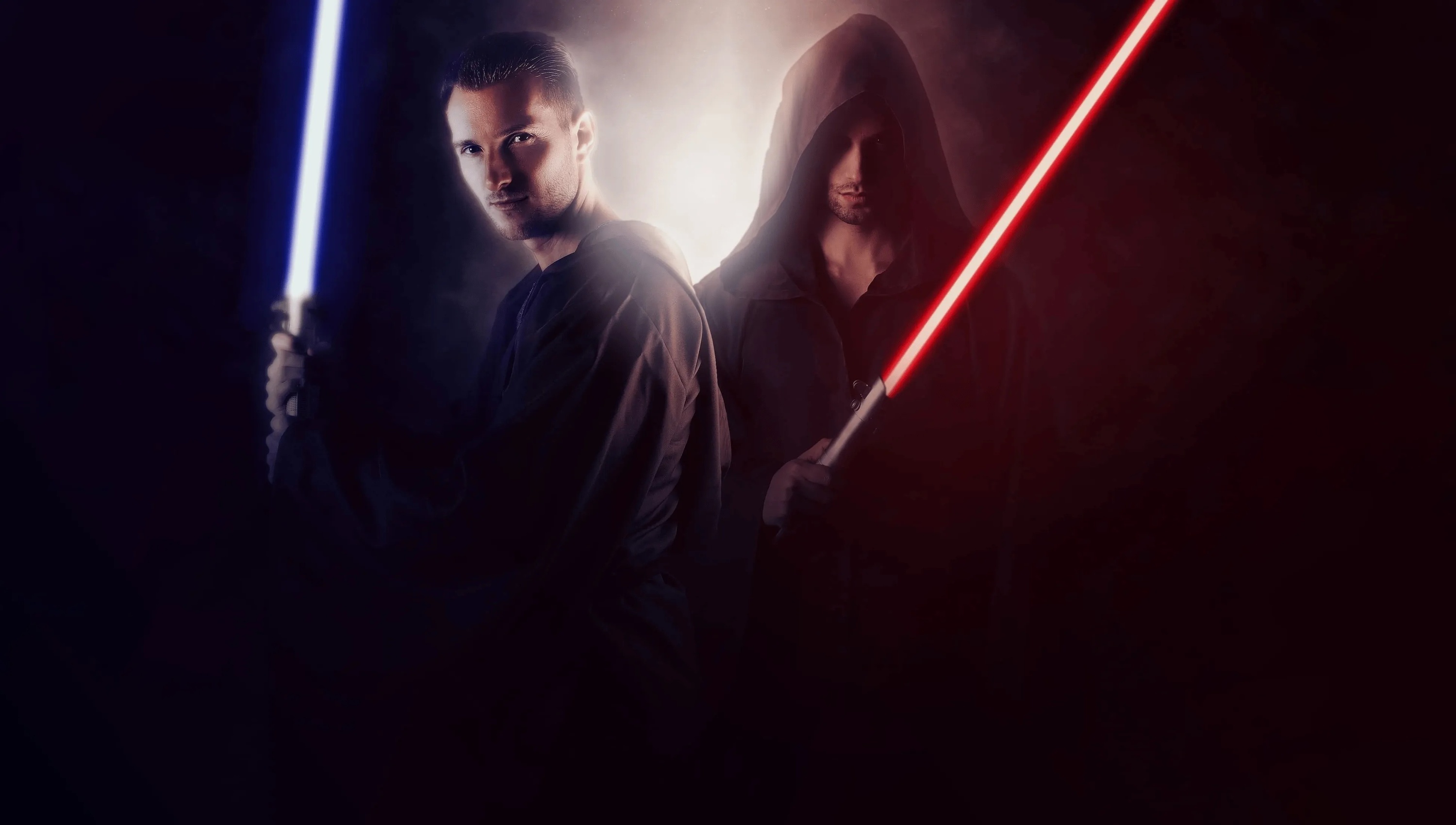 two men holding lightsabers in a dark room