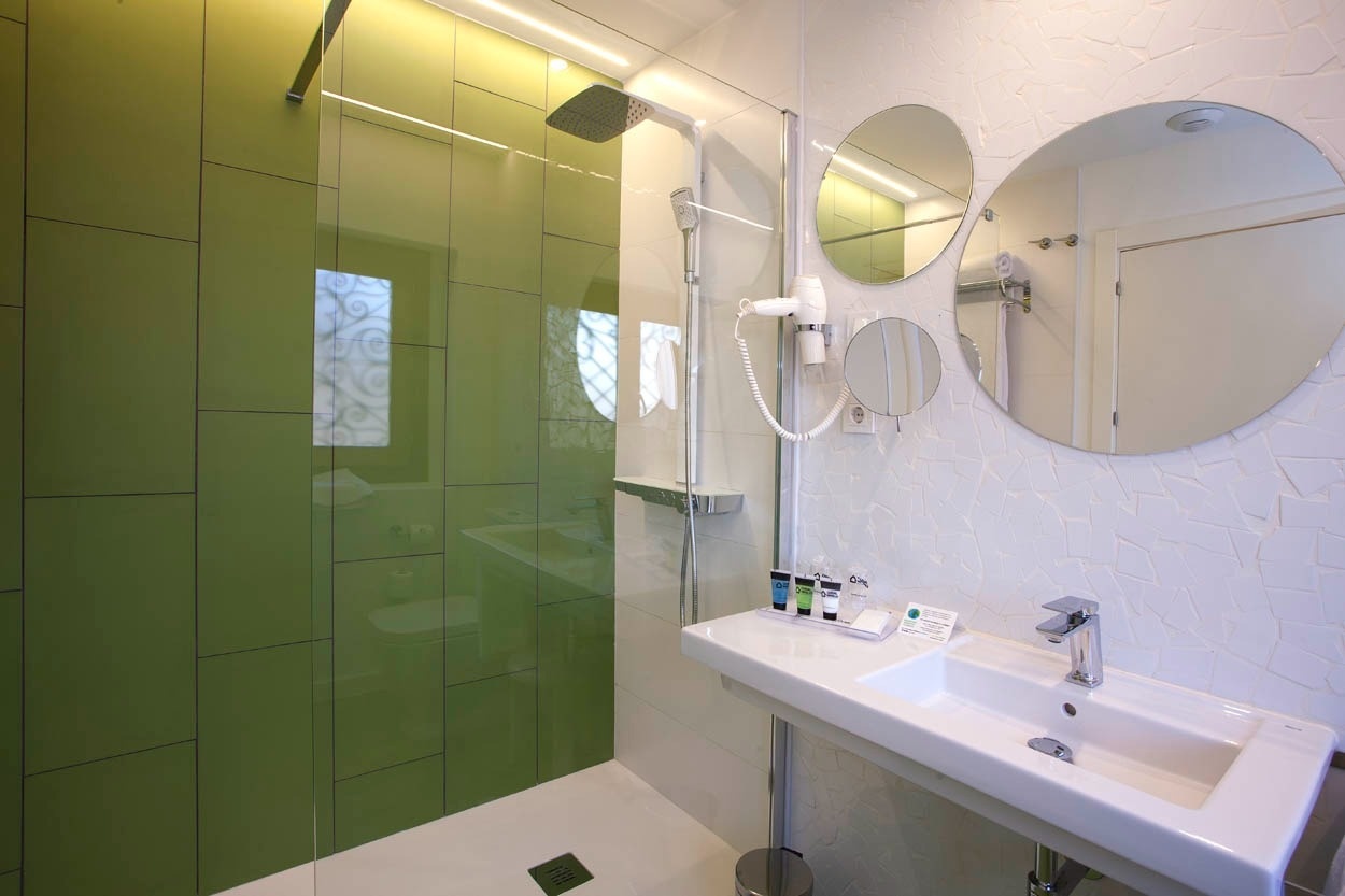 Baño moderno con ducha verde y lavabo en Casual Socarrat Valencia - Hotel cerca de la Catedral.