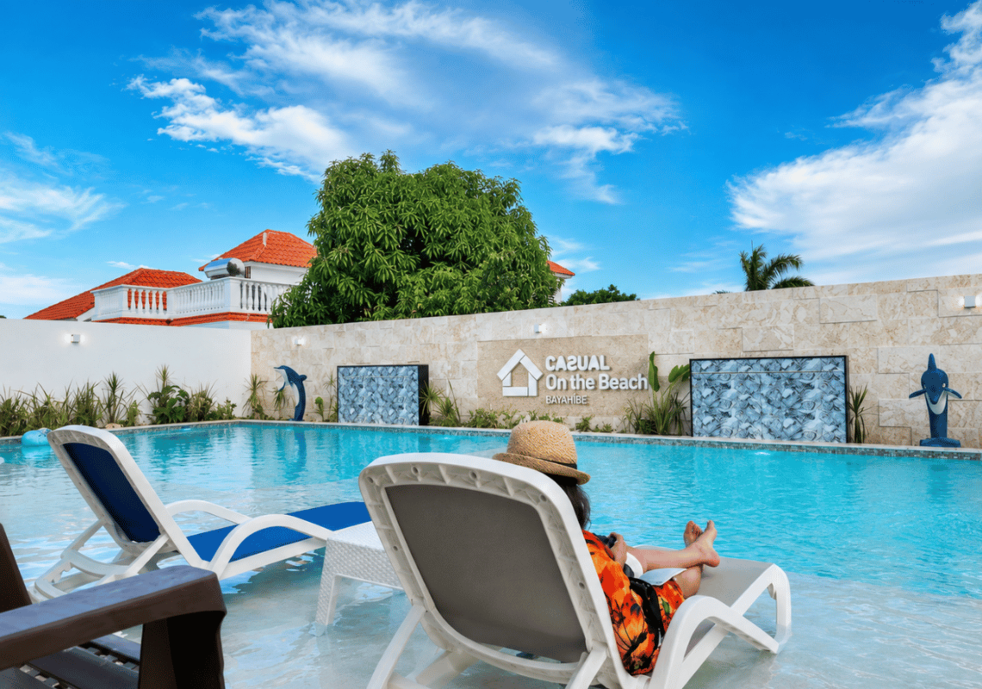 Persona relajándose en tumbona junto a piscina en hotel Casual: Corporativa Bayahíbe