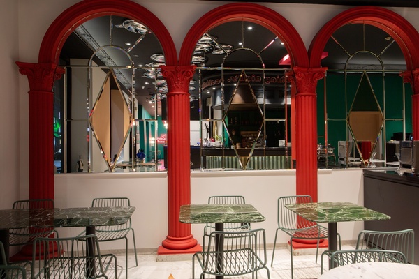 un restaurante con columnas rojas y mesas y sillas verdes