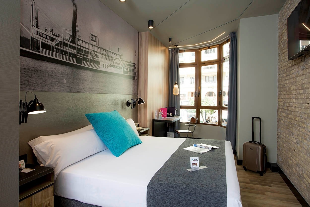 Habitación céntrica con cama cómoda y mural temático en Casual Vintage Valencia.