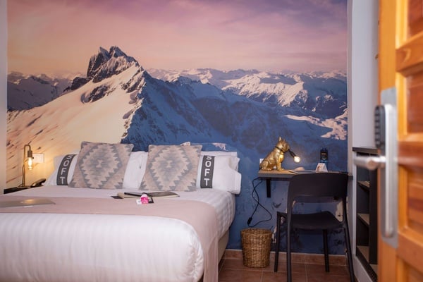 una habitación con una cama y un escritorio con una imagen de montañas en la pared