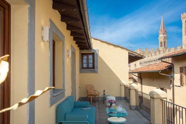 a balcony with a couch and chairs and a view of a castle