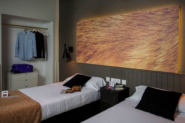 a hotel room with two beds and a purple suitcase