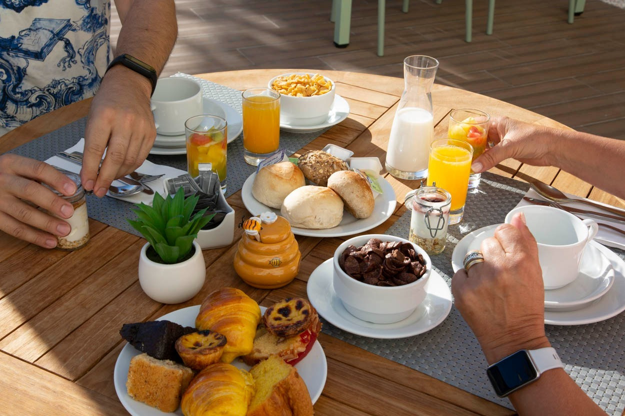 Colazione abbondante al Casual Raízes Porto - Boutique hotel, con cornetti, frutta e succhi.