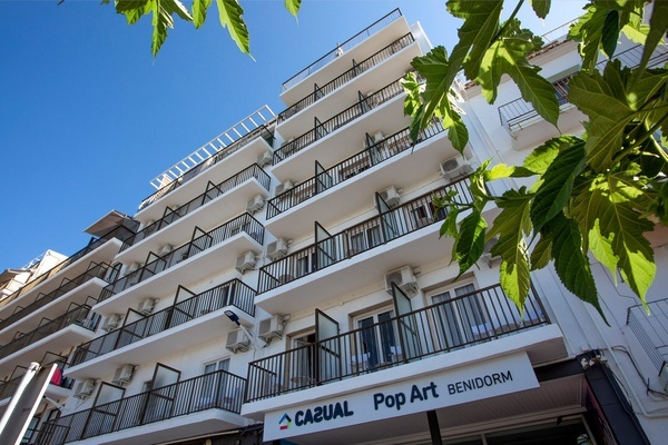 un edificio blanco con balcones y un letrero que dice casual pop art benidorm