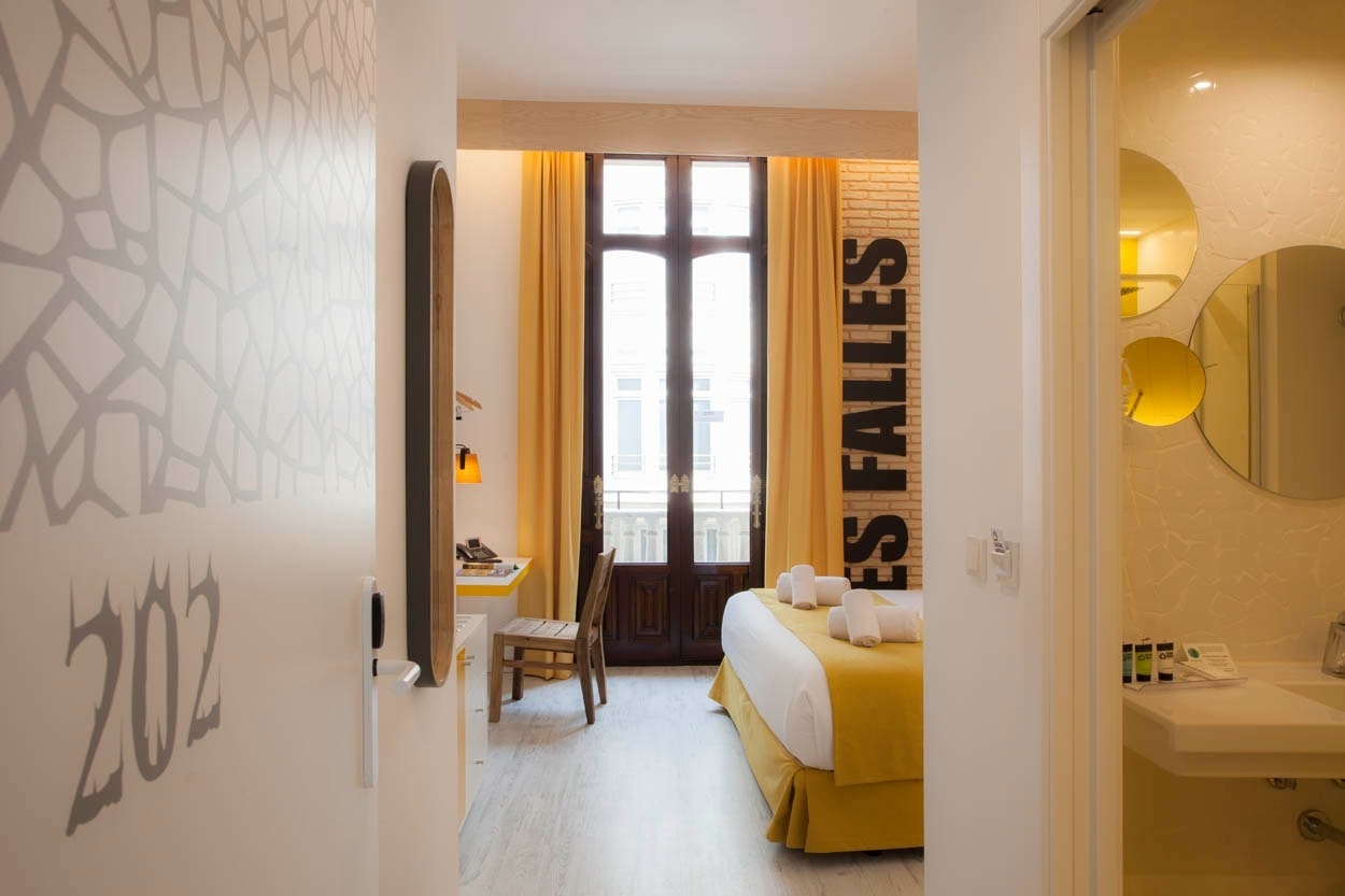Habitación moderna con cama matrimonial, escritorio y baño en Casual Socarrat Valencia.
