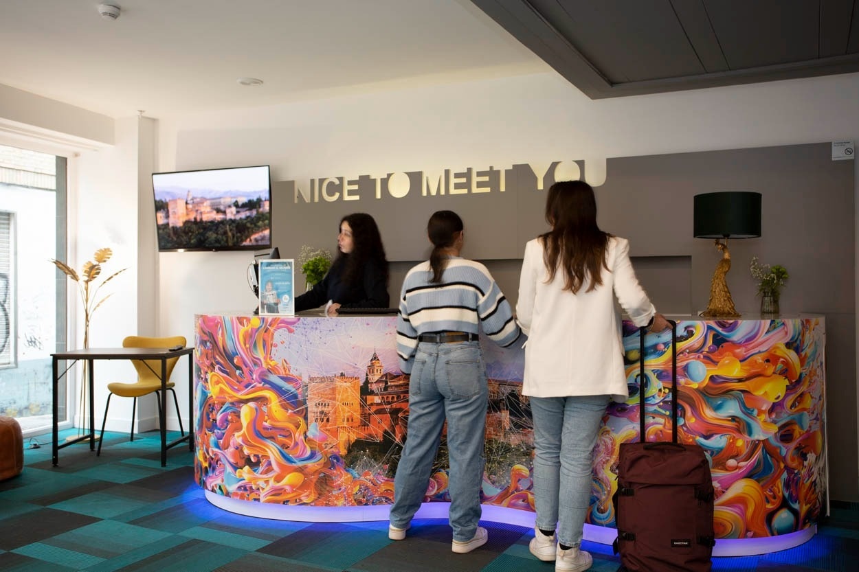 Recepción vibrante en Casual Ilbira Granada con personal y huéspedes. ¡Bienvenido a Casual Hoteles!