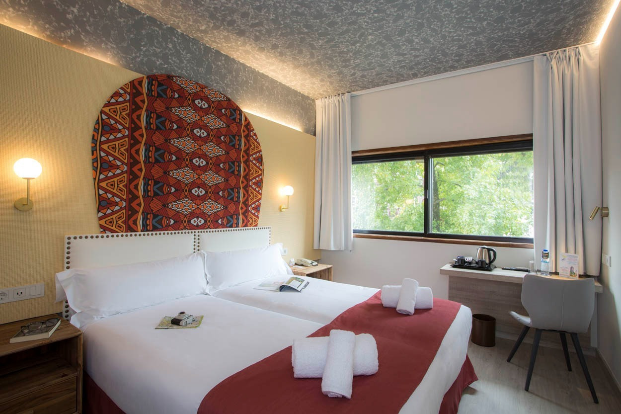 Modernes Hotelzimmer im Casual Inca Porto mit zwei Betten und Blick ins Grüne.