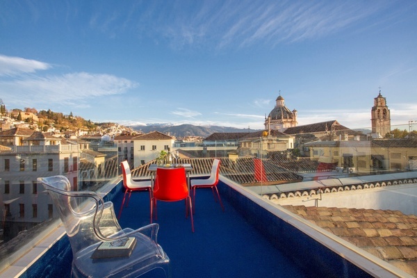 uma mesa e cadeiras vermelhas em um terraço com vista para uma cidade