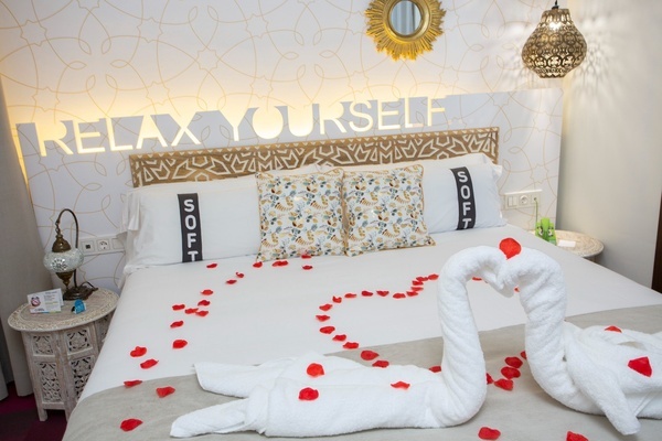 uma cama decorada com cisnes de toalhas e pétalas de rosas