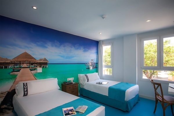 una habitación de hotel con dos camas y un mural de un muelle en el océano