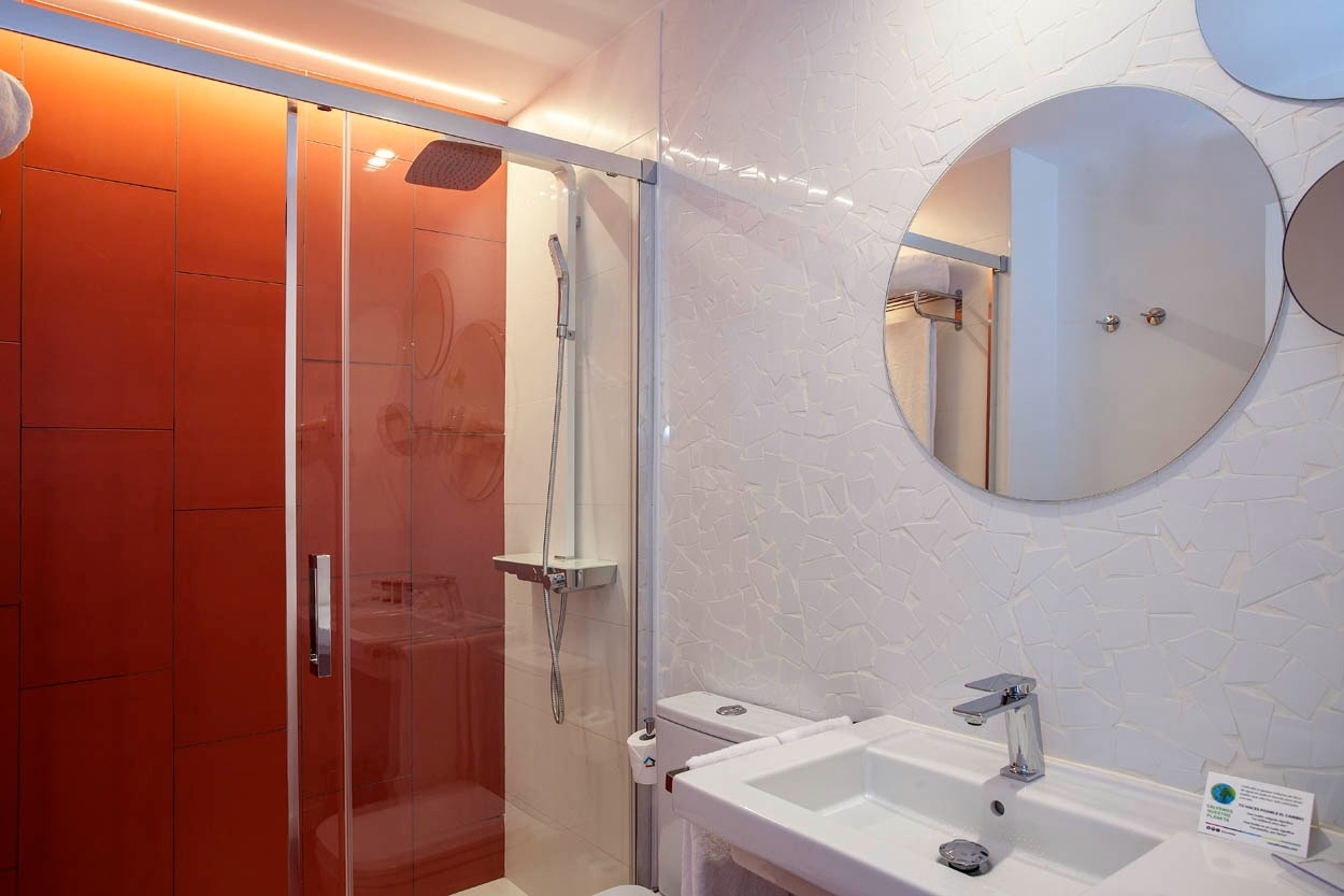 Baño moderno con ducha naranja y lavabo en Casual Socarrat Valencia - Hotel cerca de la Catedral.