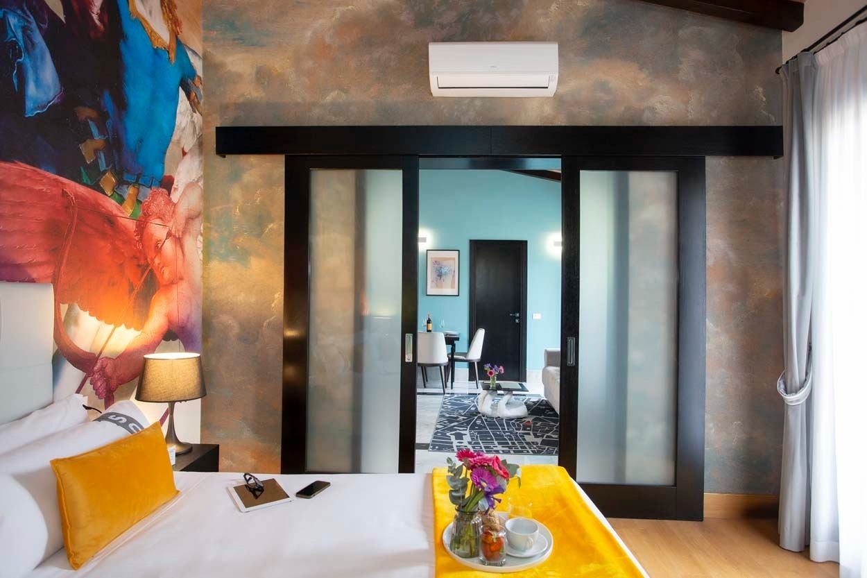 Komfortables Schlafzimmer im Casual Rinascimento Firenze - Zentrales Hotel mit Pool in Florenz, mit künstlerischer Wandgestaltung und Blick auf Wohnbereich.