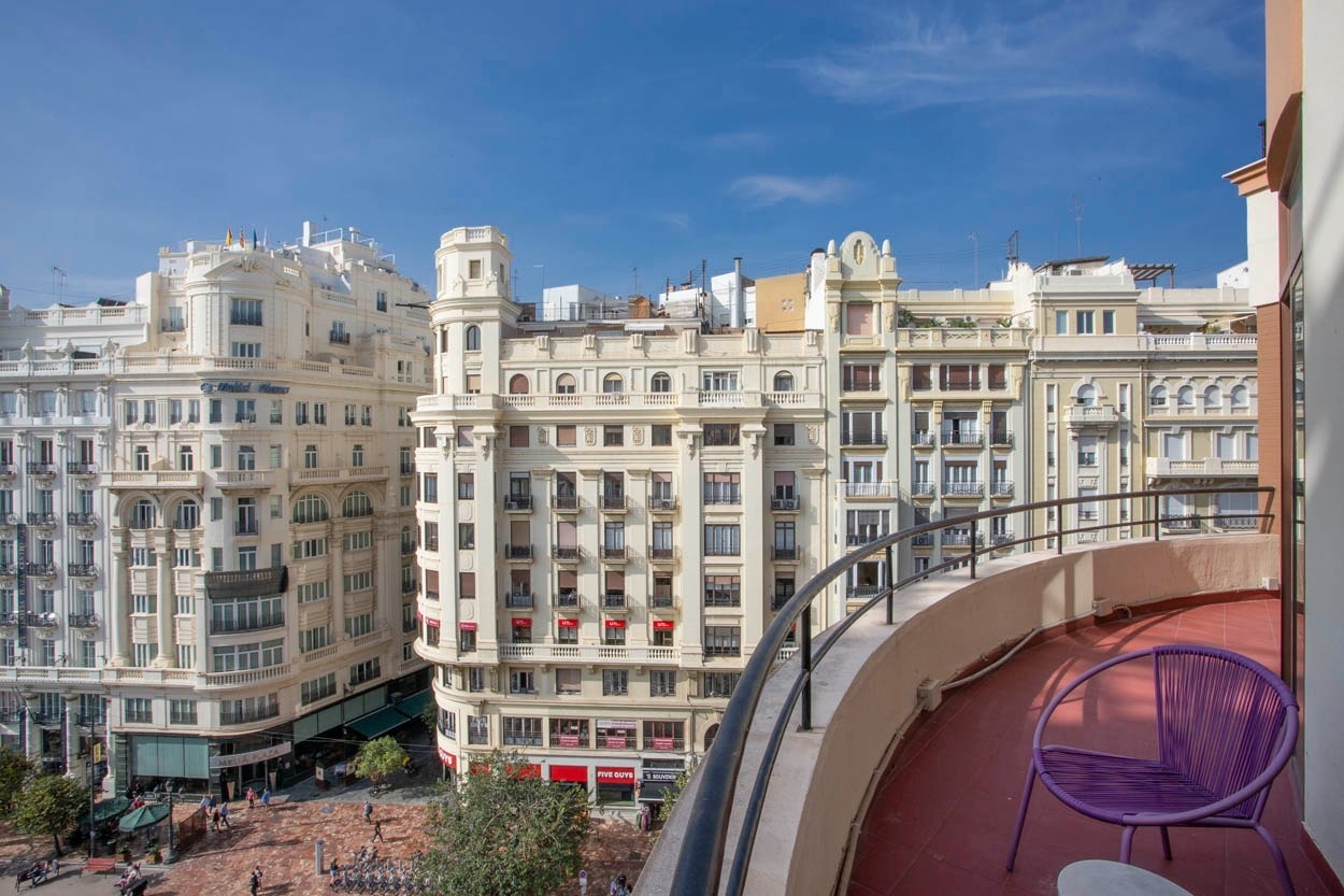 Balcón con silla morada y vistas a edificios emblemáticos en Valencia, cerca del Ayuntamiento. Casual Vintage Valencia.