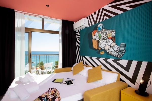 una habitación con una cama y un sofá con una pintura de un astronauta en la pared