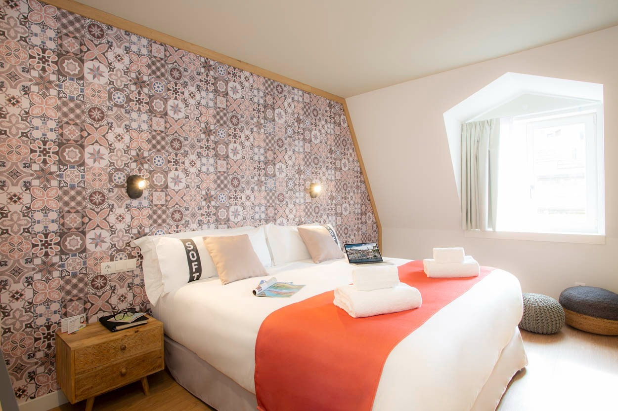 Camera accogliente con letto king size, carta da parati decorativa e vista sulla città, perfetto per un soggiorno al Casual Raízes Porto.