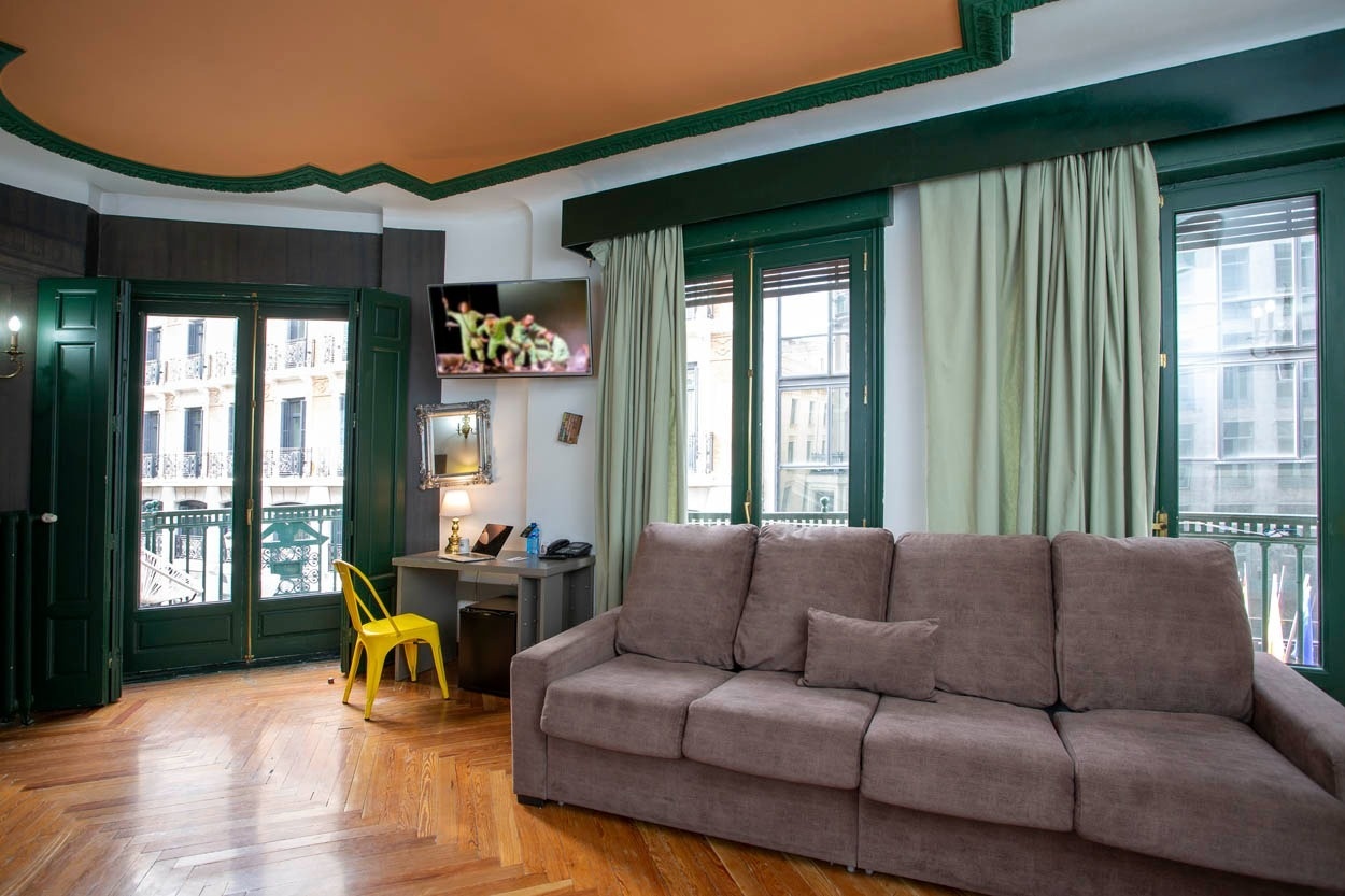 Gemütliches Wohnzimmer mit Sofa und Schreibtisch im Casual del Teatro Madrid – Boutique-Hotel nahe Gran Vía.