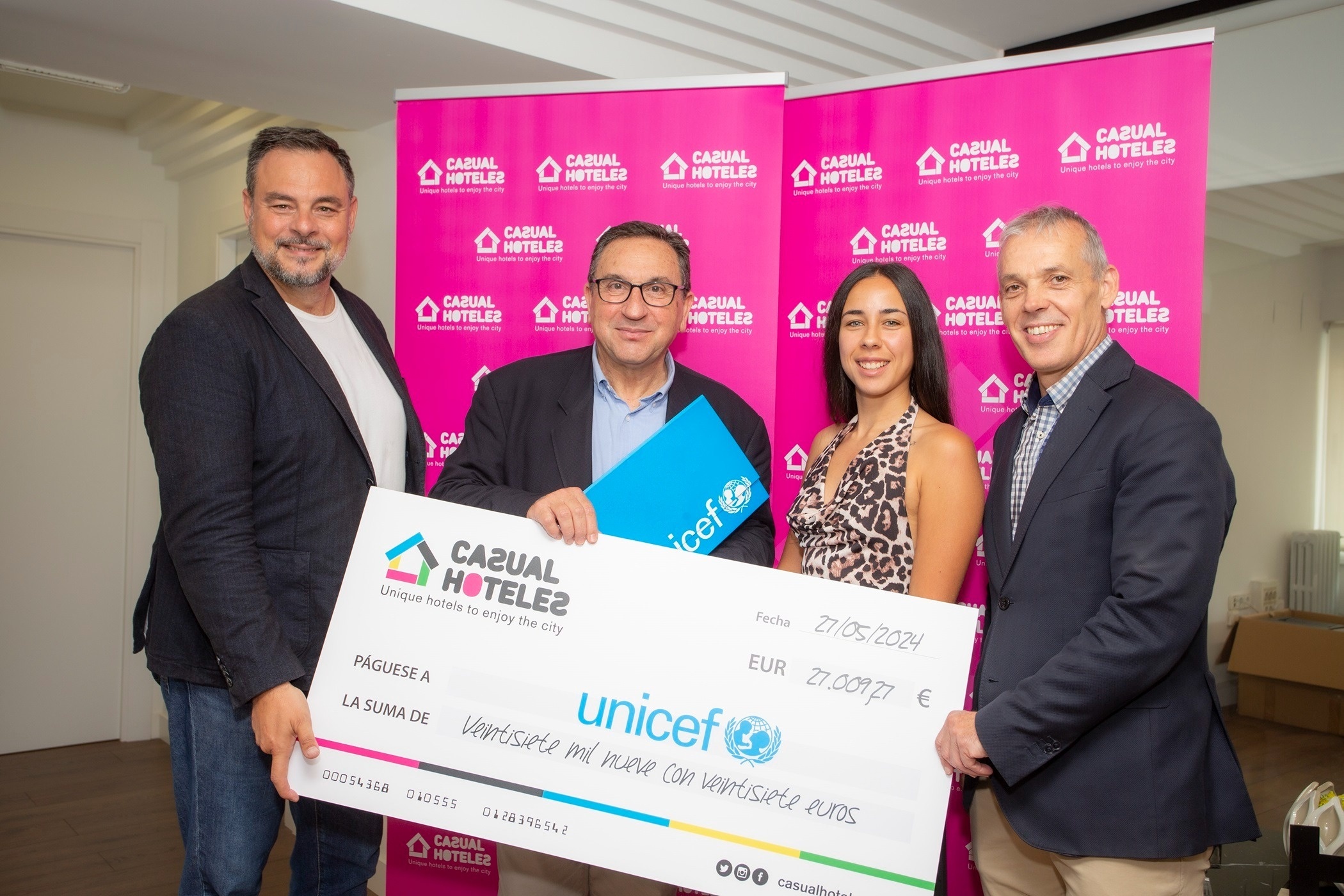 tres hombres y una mujer sostienen un cheque de unicef