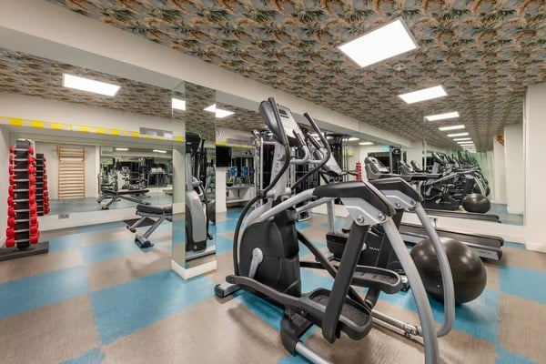 een grote sportschool met veel apparaten en spiegels