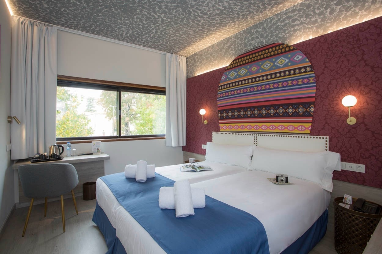 Gemütliches Zimmer mit zwei Betten und farbenfrohem Wanddekor im Casual Inca Porto - Zentrales Hotel in Porto.