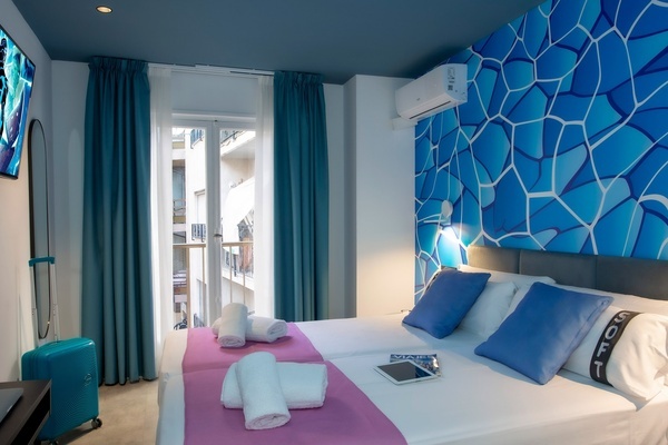 una habitación de hotel con una cama doble y una maleta azul