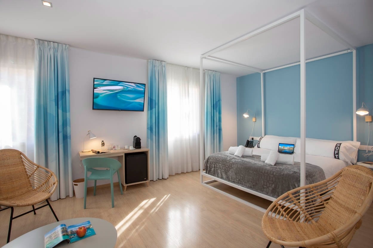 Stijlvolle hotelkamer Casual Colours Barcelona met zeeblauwe gordijnen en ligstoelen.