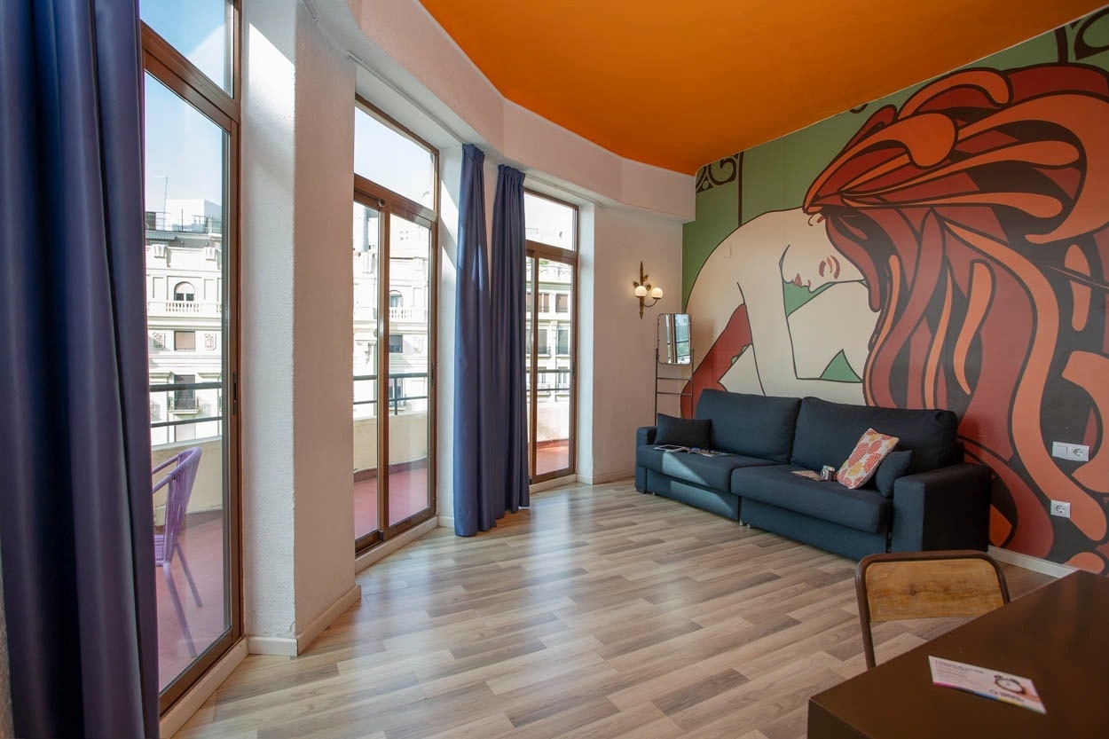 Sofá azul frente a mural artístico en Casual Vintage Valencia. Hotel céntrico junto al Ayuntamiento.