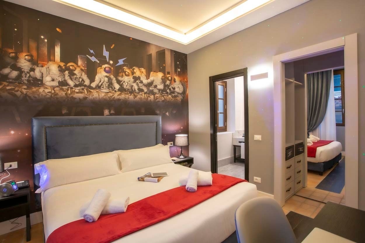 Bequemes Bett mit Astronauten-Wandbild, im Casual Rinascimento Firenze Hotel mit Pool.