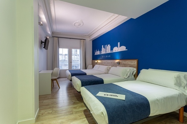 a hotel room with three beds and a blue wall