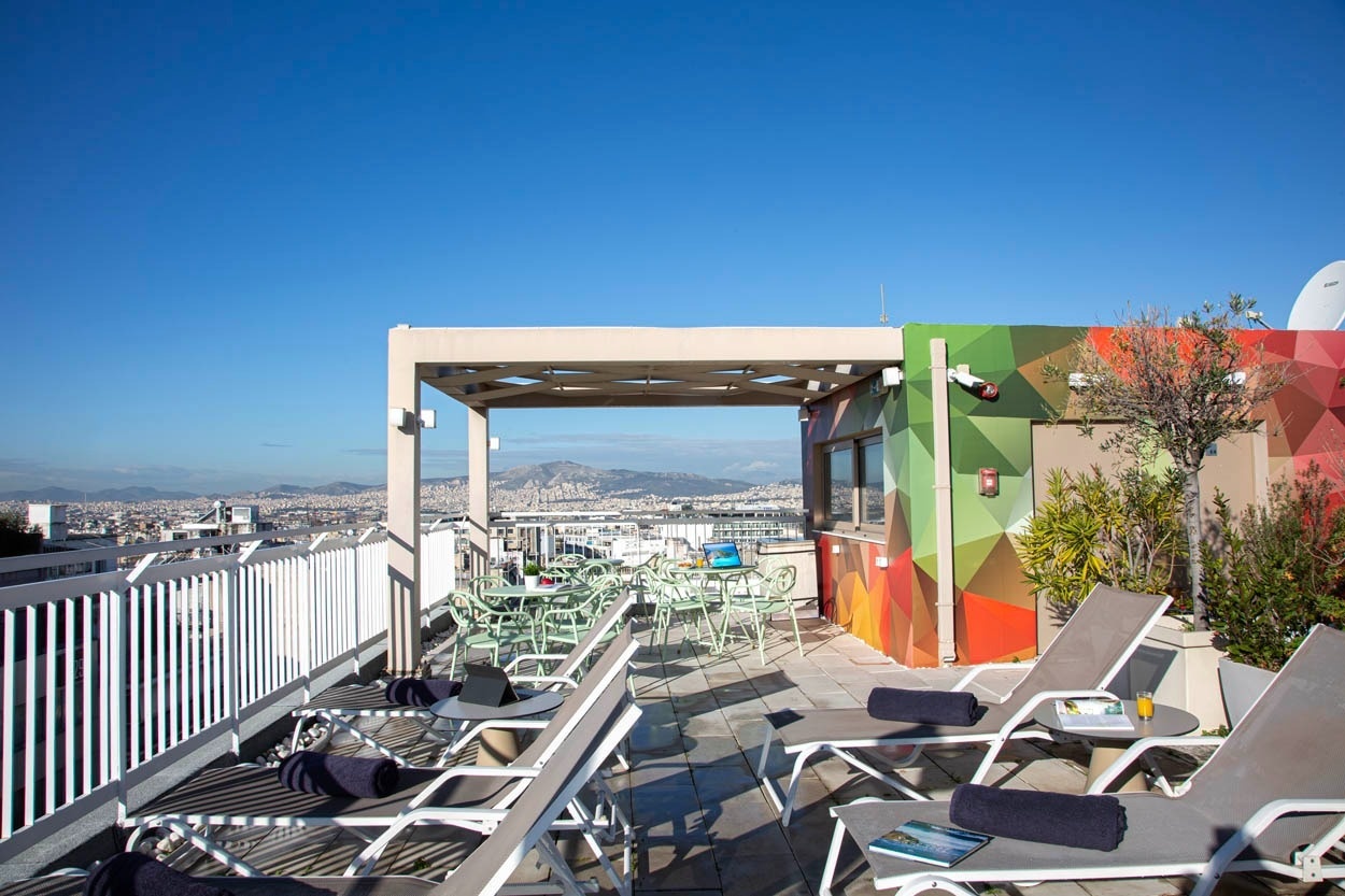 Entspannen Sie auf der Dachterrasse des Casual Kubic Athens: Loungemöbel, Blick auf Athen, Smart Hotel.