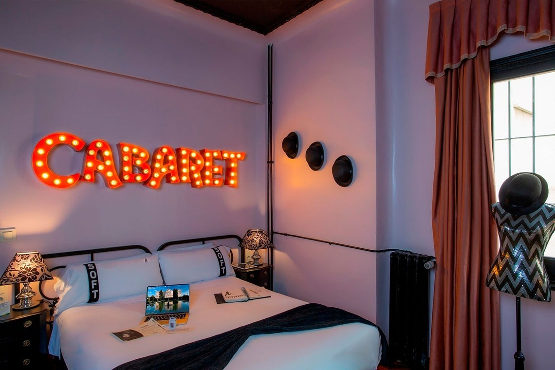 a bedroom with a cabaret sign above the bed