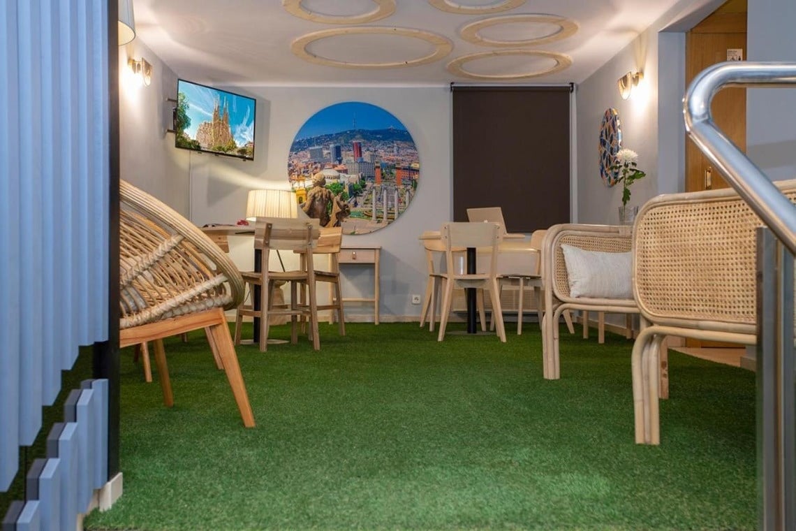 una sala de estar con sillas y mesas y una pintura de una ciudad en la pared