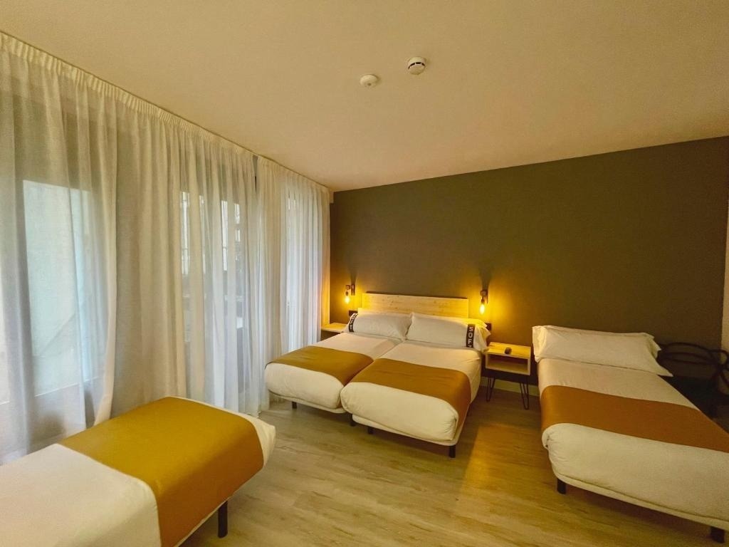 una habitación con tres camas y una ventana
