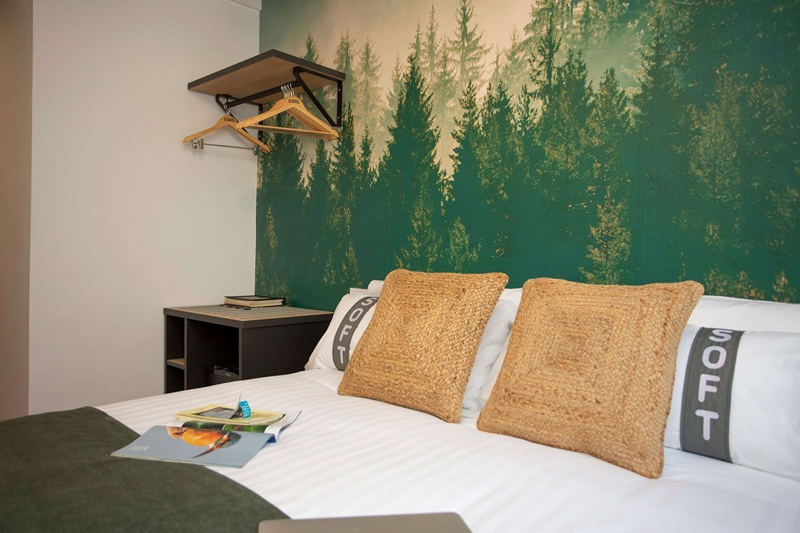 Zwei Kissen auf einem Bett im Casual Natura Valencia, inspiriert von der Natur. Mit Wandbild im Wald-Stil.