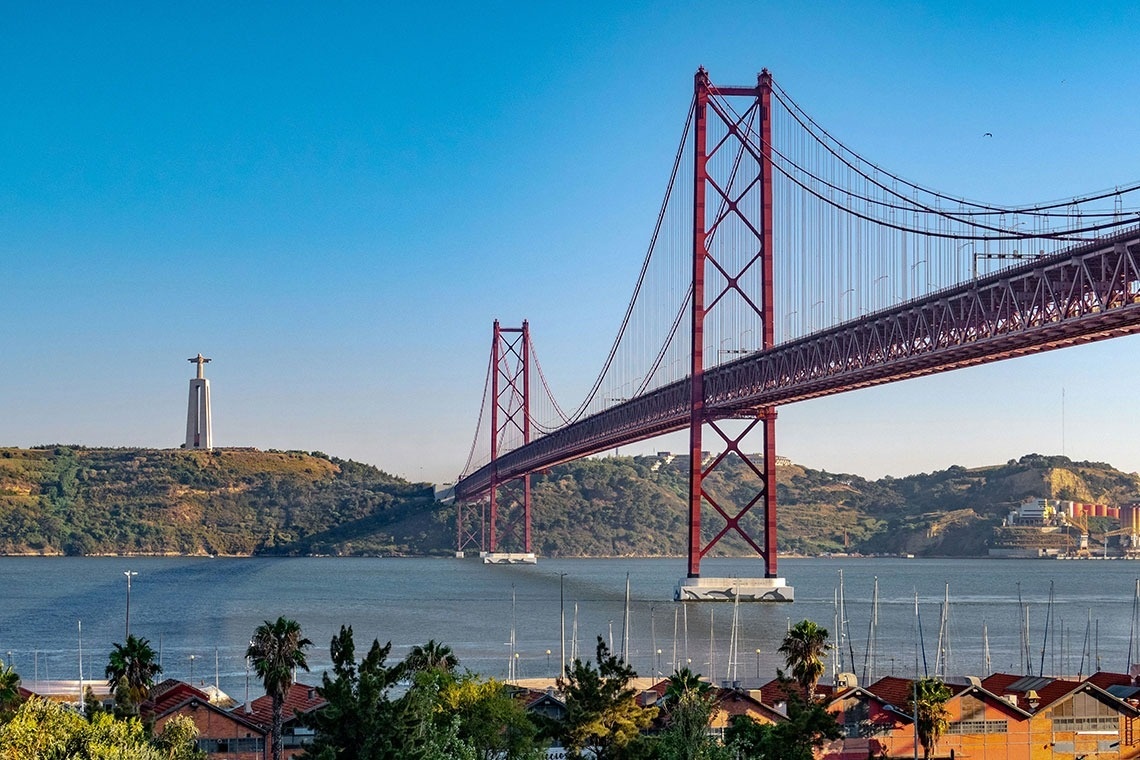 un puente rojo sobre un río con una estatua en el fondo
