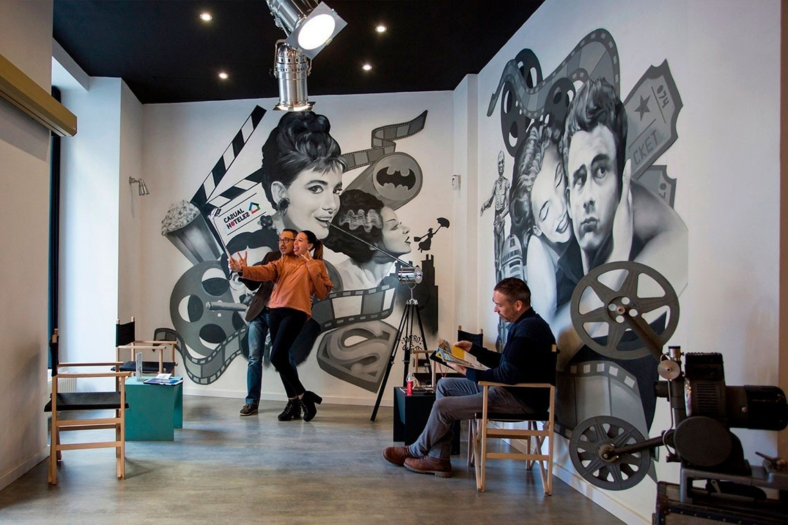 un hombre y una mujer posan para una foto en una habitación con un mural de estrellas de cine