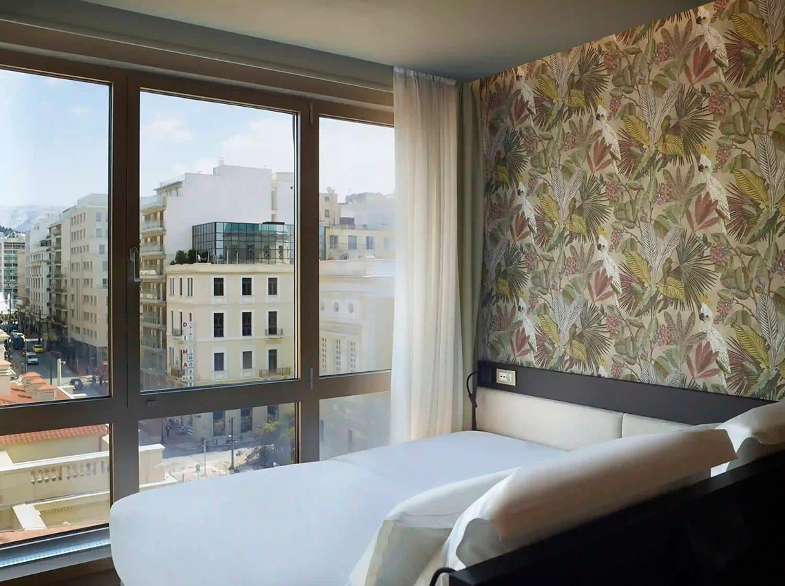 una habitación de hotel con una cama y una gran ventana