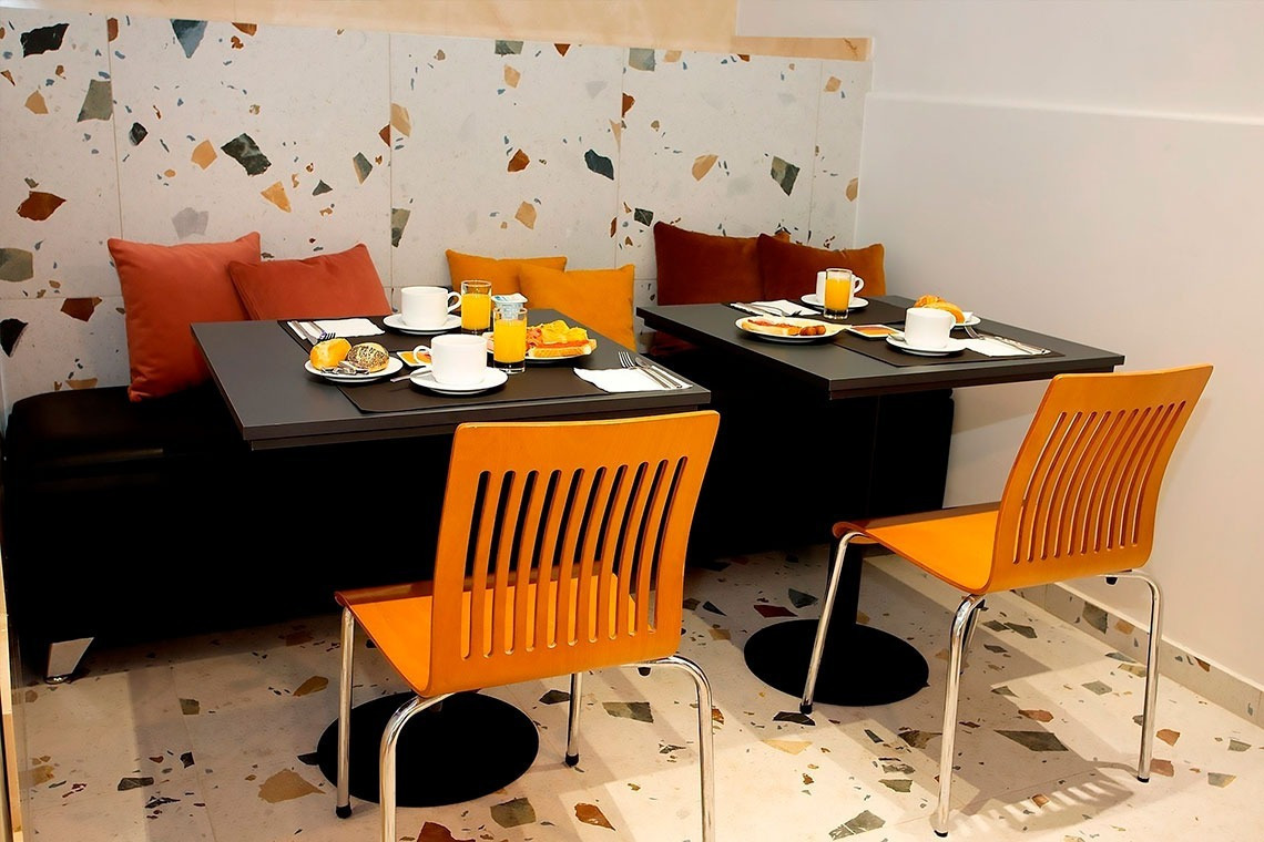 un comedor con mesas y sillas naranjas y platos de comida