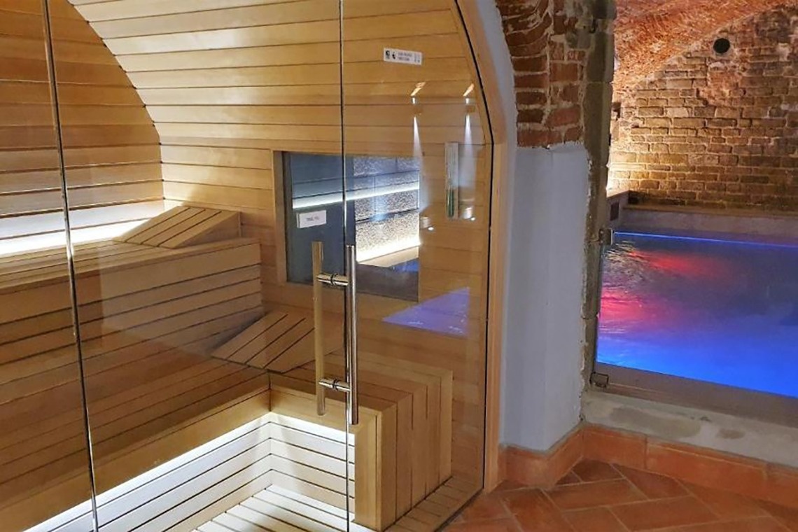 una sauna con una puerta de vidrio que conduce a una piscina