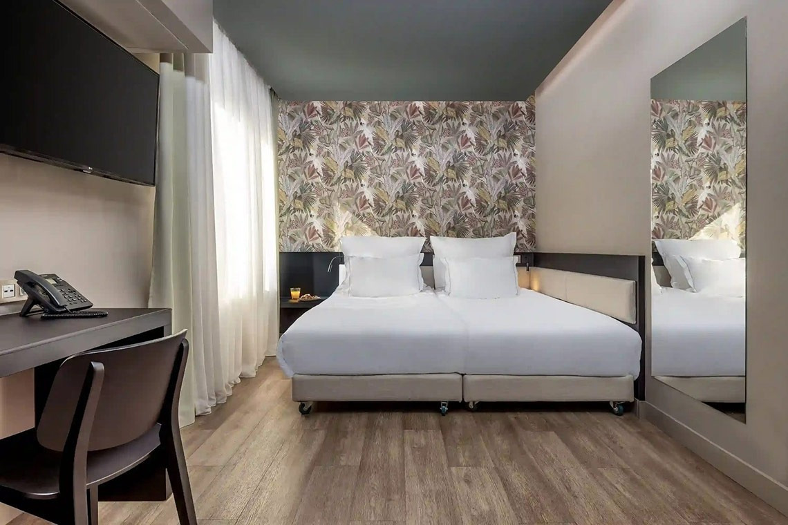 una pequeña habitación de hotel con una cama y un escritorio