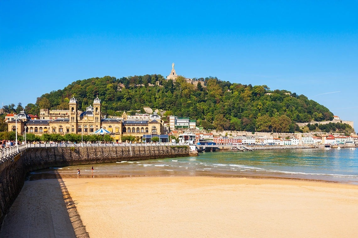 una playa con un gran edificio en la cima de una colina