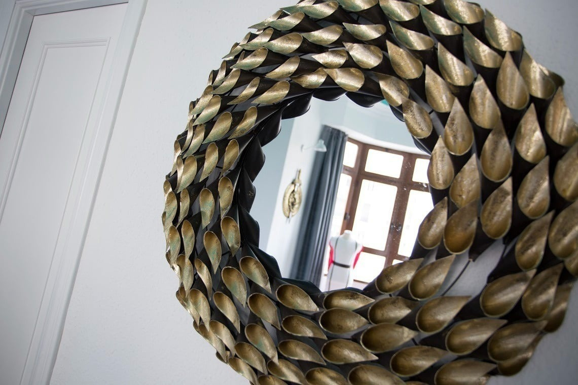 a round mirror with gold leaves on it